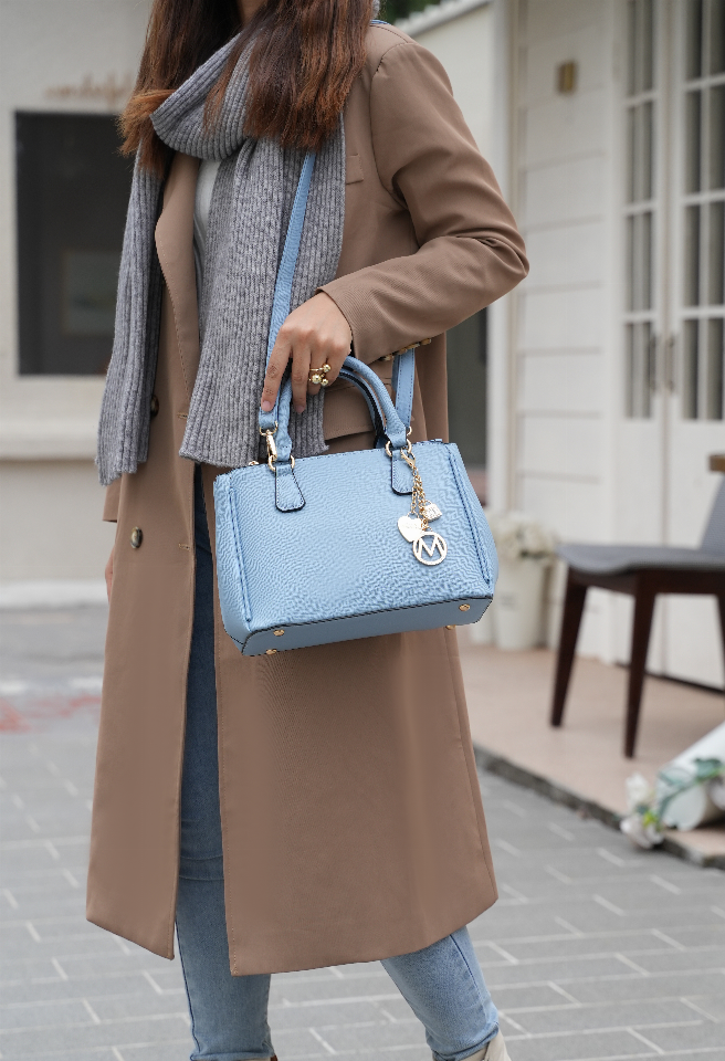 Light blue satchel bag with chain charm and wallet pocket; held by top handles