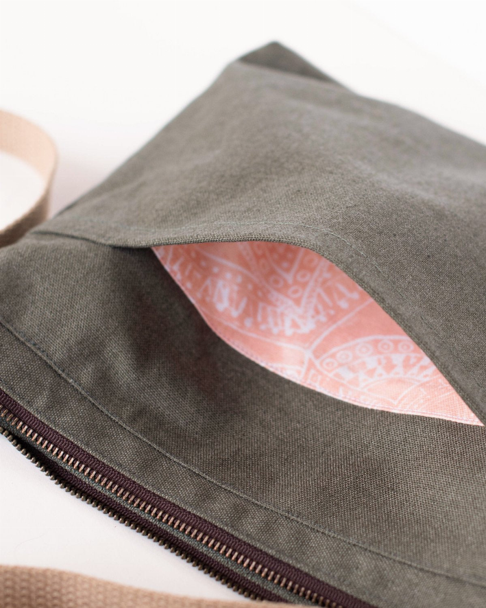 Olive crossbody bag showing pink patterned lining and long zipper along side