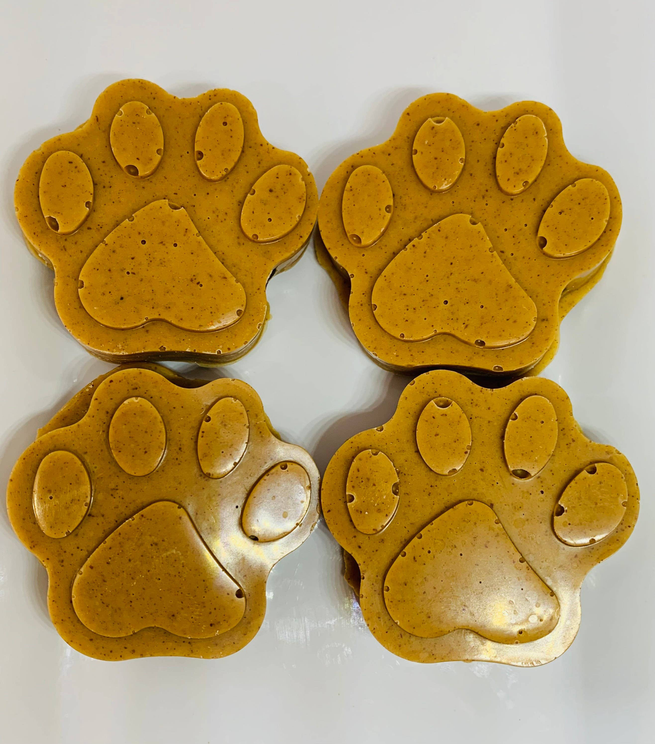 Paw-shaped dog treats, golden-yellow with embossed paw pads and claws