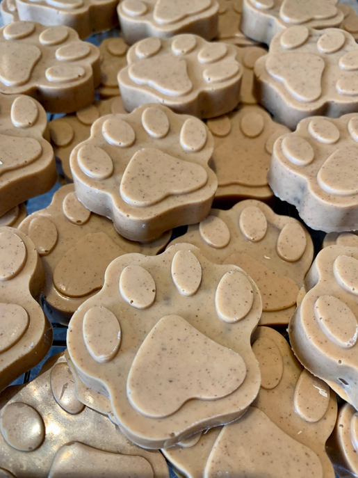 Paw-shaped dog treats with pale tops and darker centers, piled