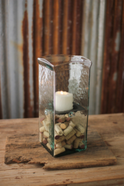 Square clear glass candle hurricane with white pillar candle inside decorative filler