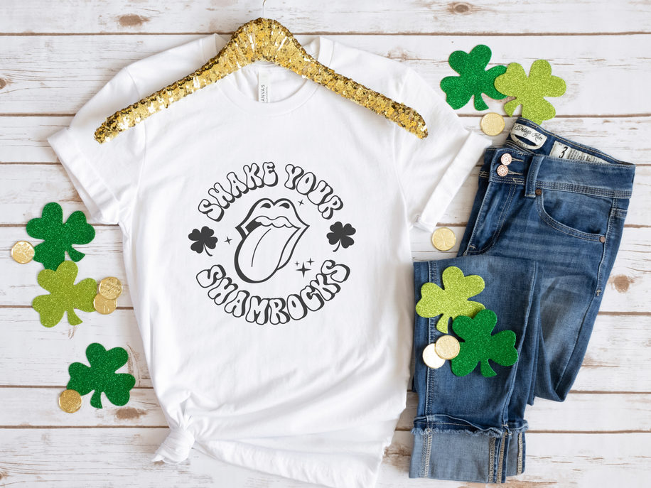 White graphic T-shirt with 'Shake Your Shamrocks' text and clover mouth icon