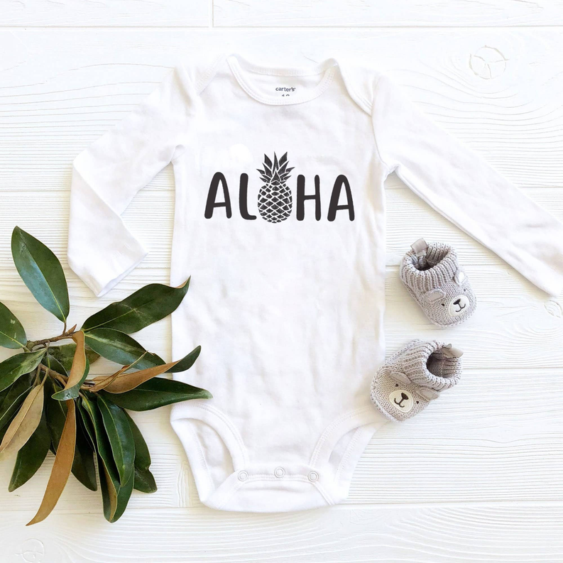White long-sleeve baby onesie with 'Aloha' graphic and snap crotch closure