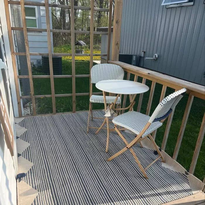 Outdoor area rug with navy-and-ivory vertical linear stripes and tassel-edge corners