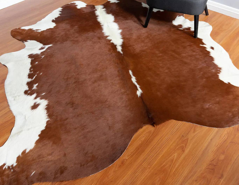 Brown and white cowhide area rug with uneven patch pattern and fur trim