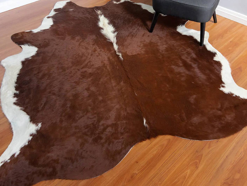 Brown cowhide rug with white edging and irregular fur patches