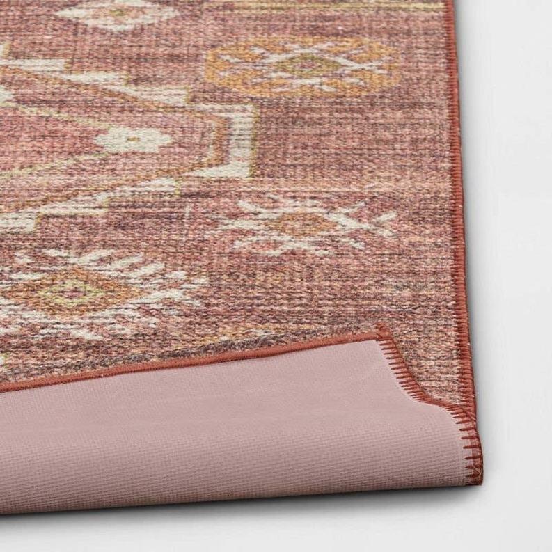 Rust rug corner with trimmed edge and textured distressed geometric pattern