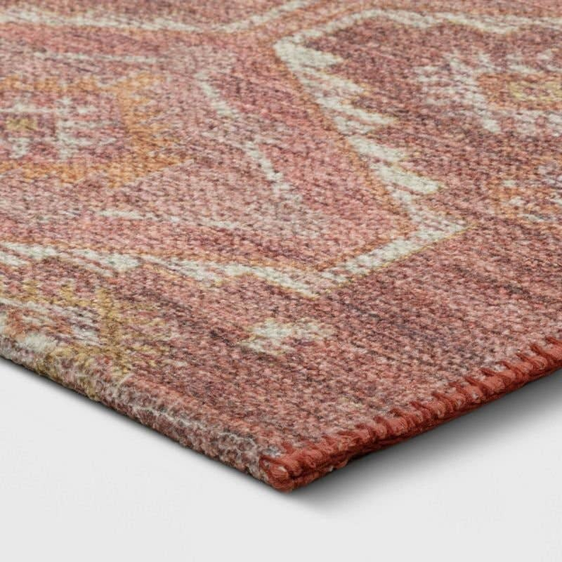 Rust rug corner close-up with distressed diamond motifs and textured flat weave