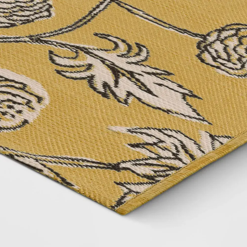 Yellow area rug close-up with black and white floral medallion motif and border