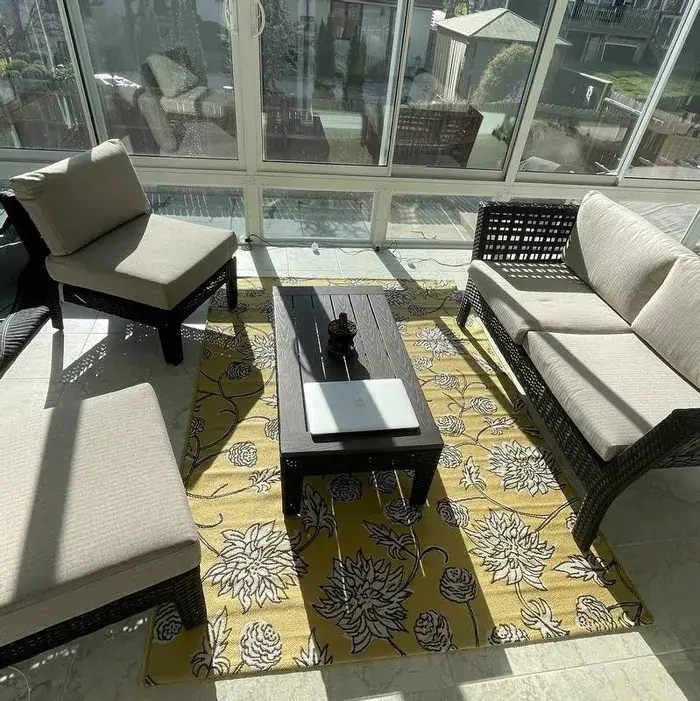 Yellow outdoor area rug on patio floor with white floral print and dark accents
