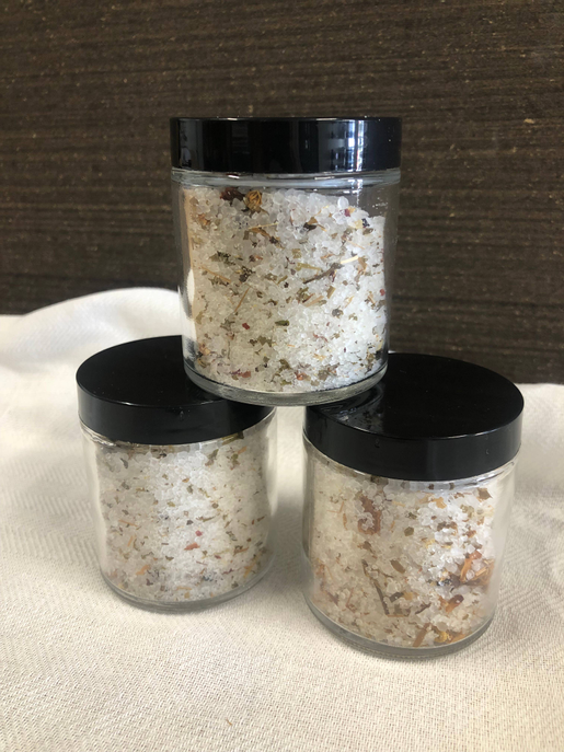 Botanical tea salt soak jar set with black lids, granules visible in three containers