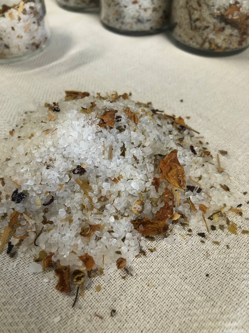 Botanical tea salt soak crystals with dried botanicals scattered on cloth