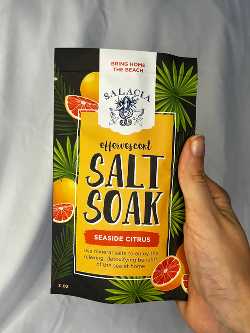 Seaside citrus effervescent salt soak pouch, 3 oz, held up with black and green label.