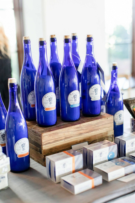Multiple blue glass salt soak bottles on a wooden crate with labels and boxes