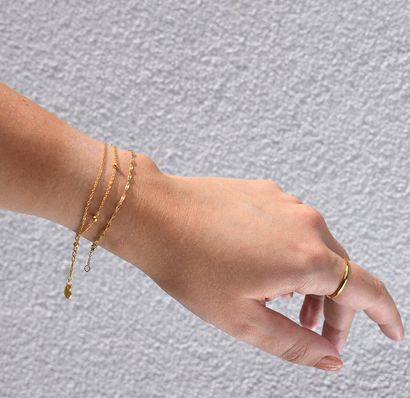 Gold-tone double chain bracelet on wrist with dangling heart charm