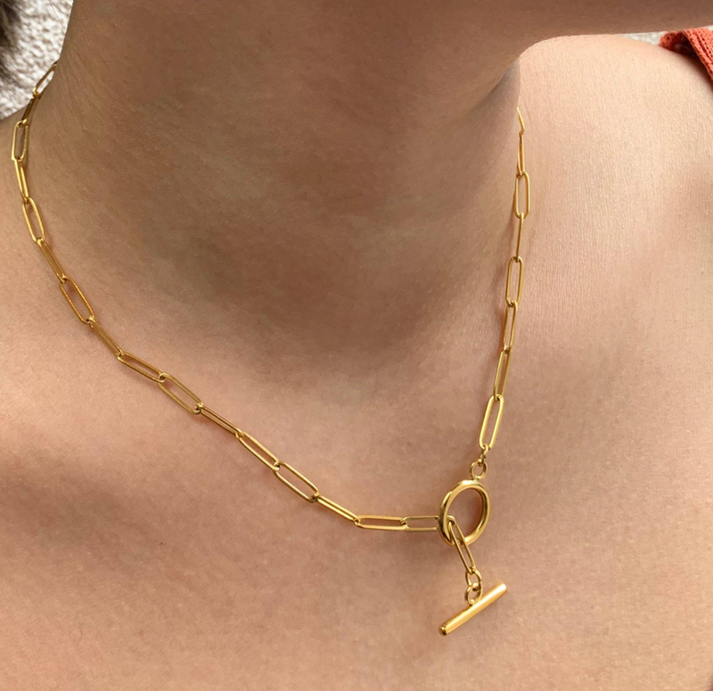 Gold paperclip chain necklace on neck with round toggle clasp and bar charm