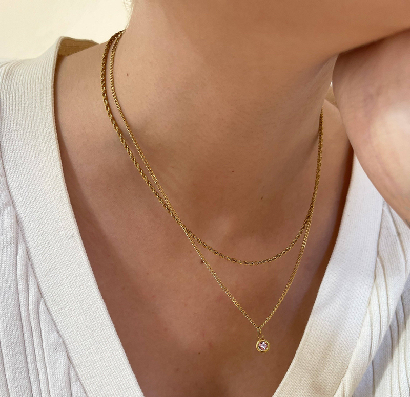 Gold layered chain pendant necklace with round pink birthstone charm at center