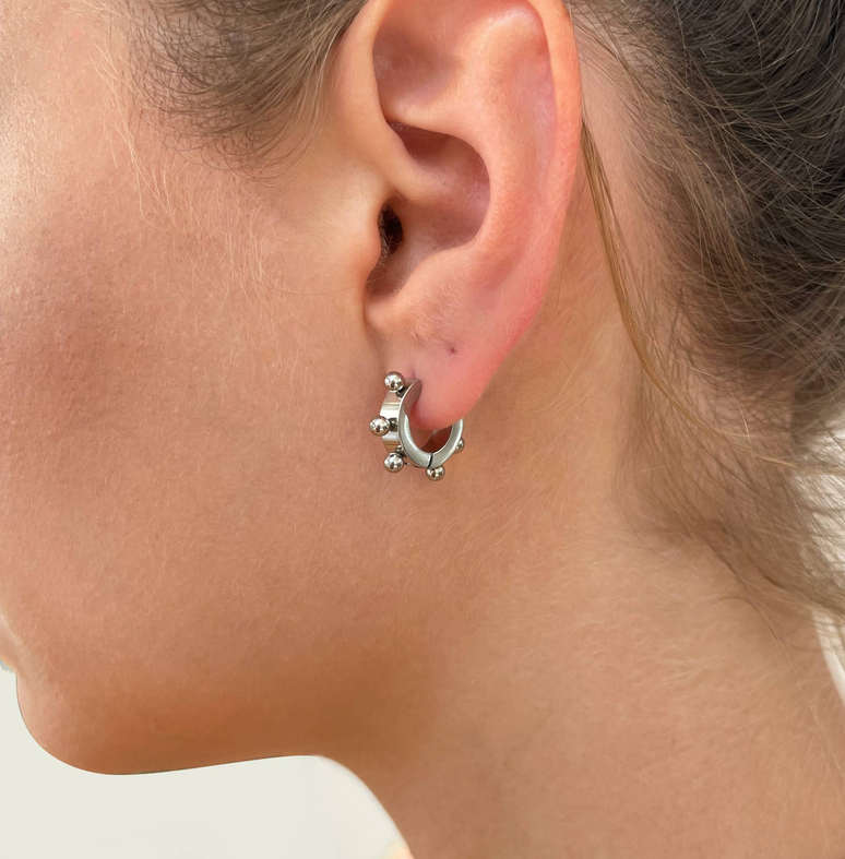 Silver huggie hoop earrings with small gem accents, worn on ear