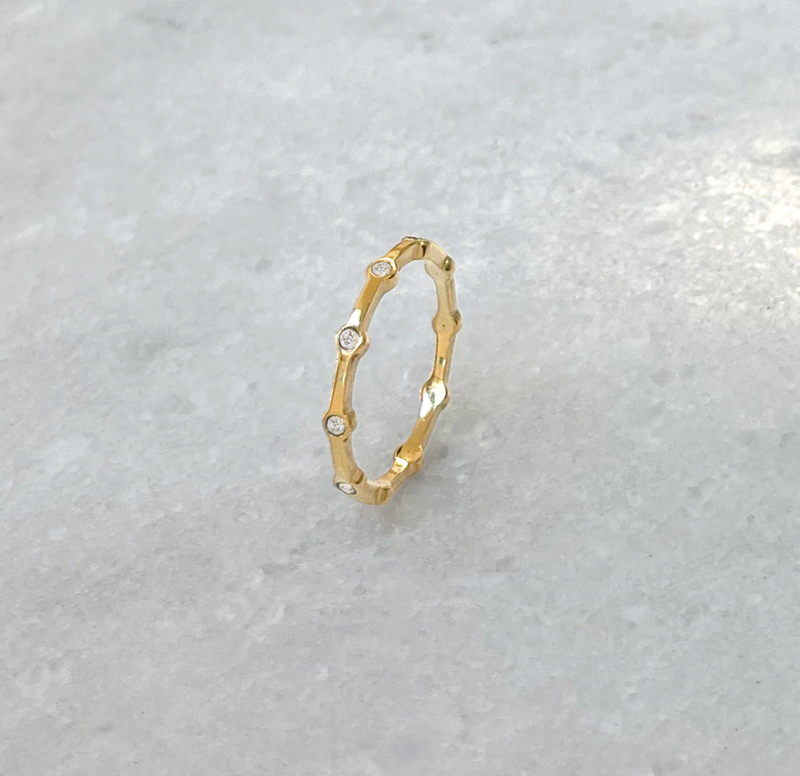 Gold-tone curved band ring with small round pave stones and open center