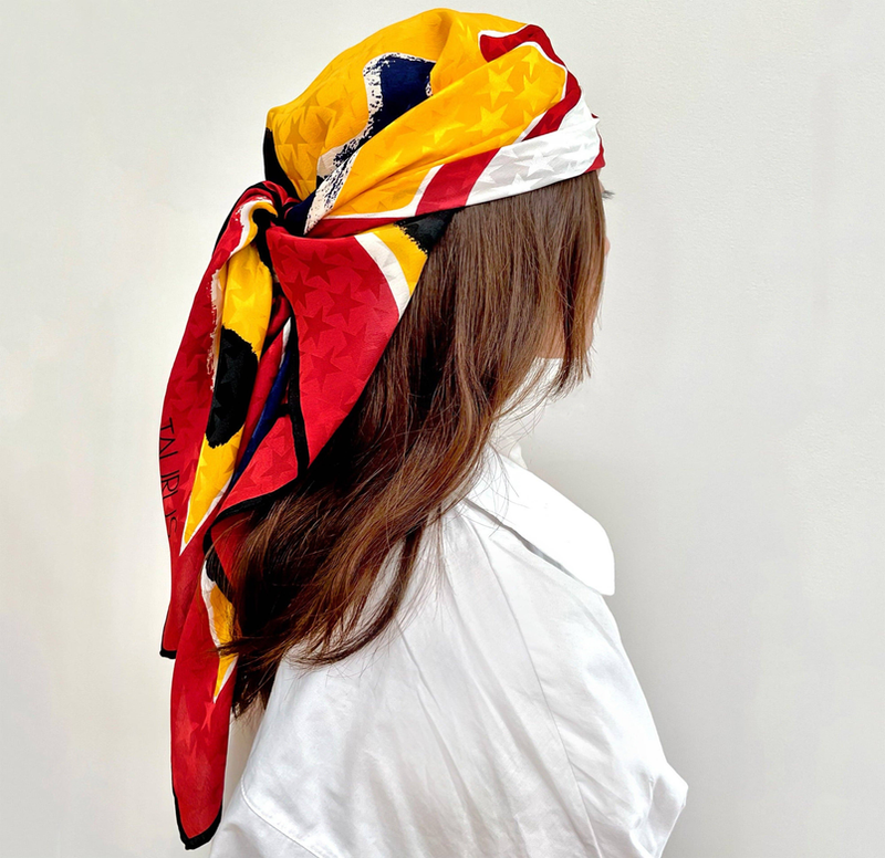 Yellow and red silk scarf with geometric print and black border, worn on head