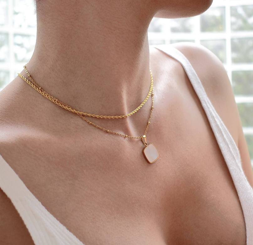 Thin gold rope chain necklace with small geometric charm at center