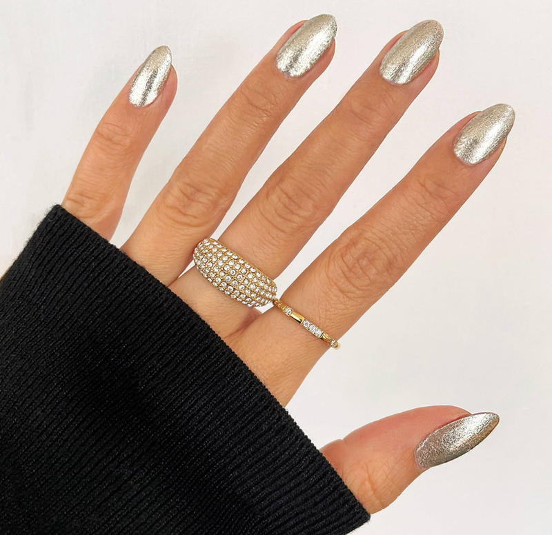 Gold-tone pave ring on finger with matching crystal band; silver nails manicure