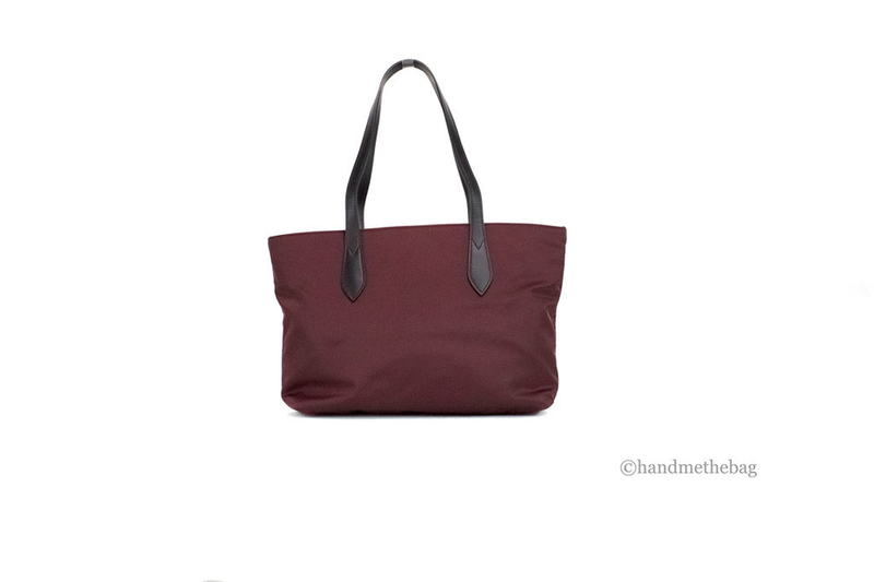 Burgundy nylon tote bag with black logo branding and black leather-look top handles