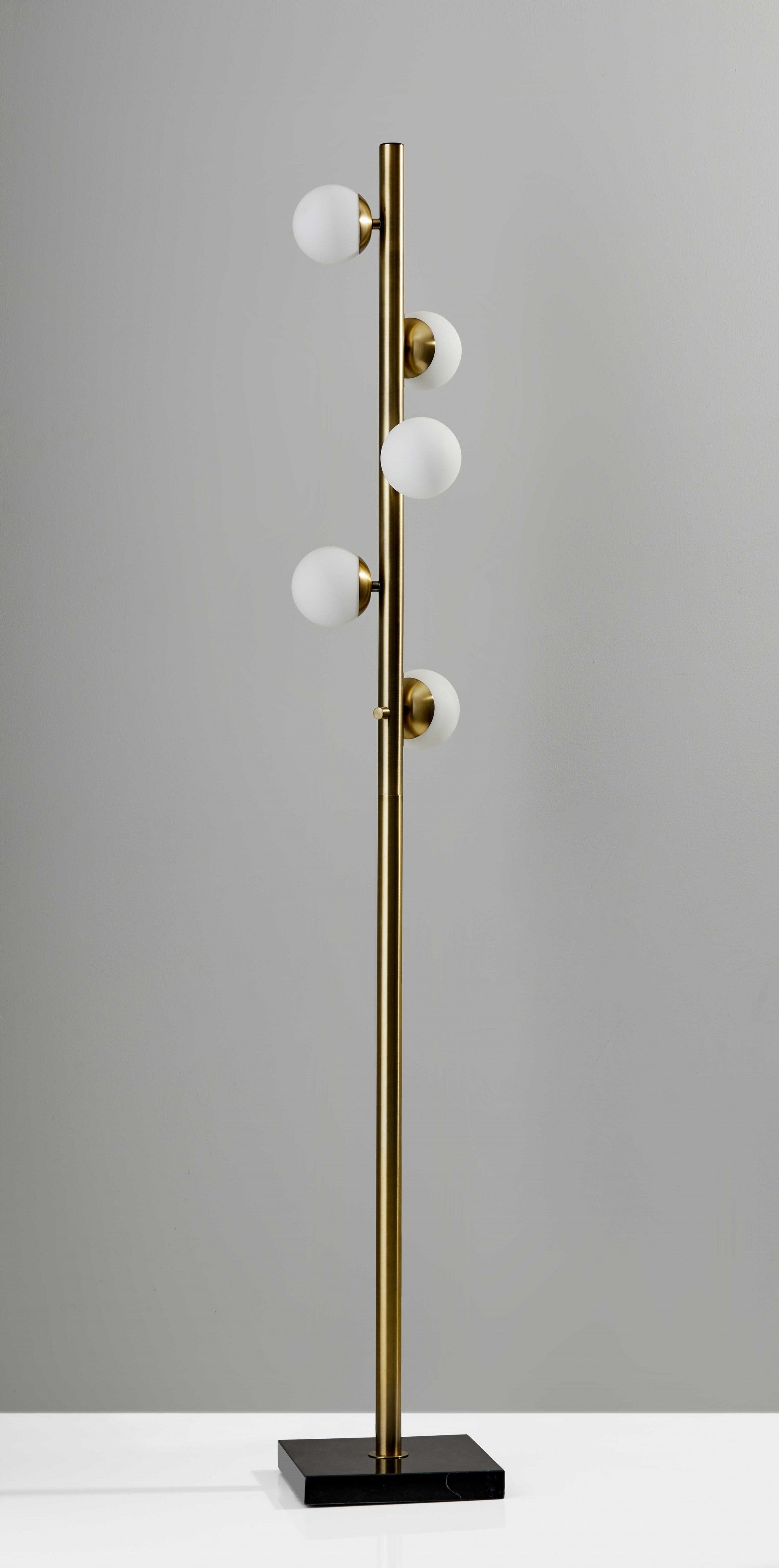 Modern brass floor lamp with four white glass globes, sleek design, and black marble base.