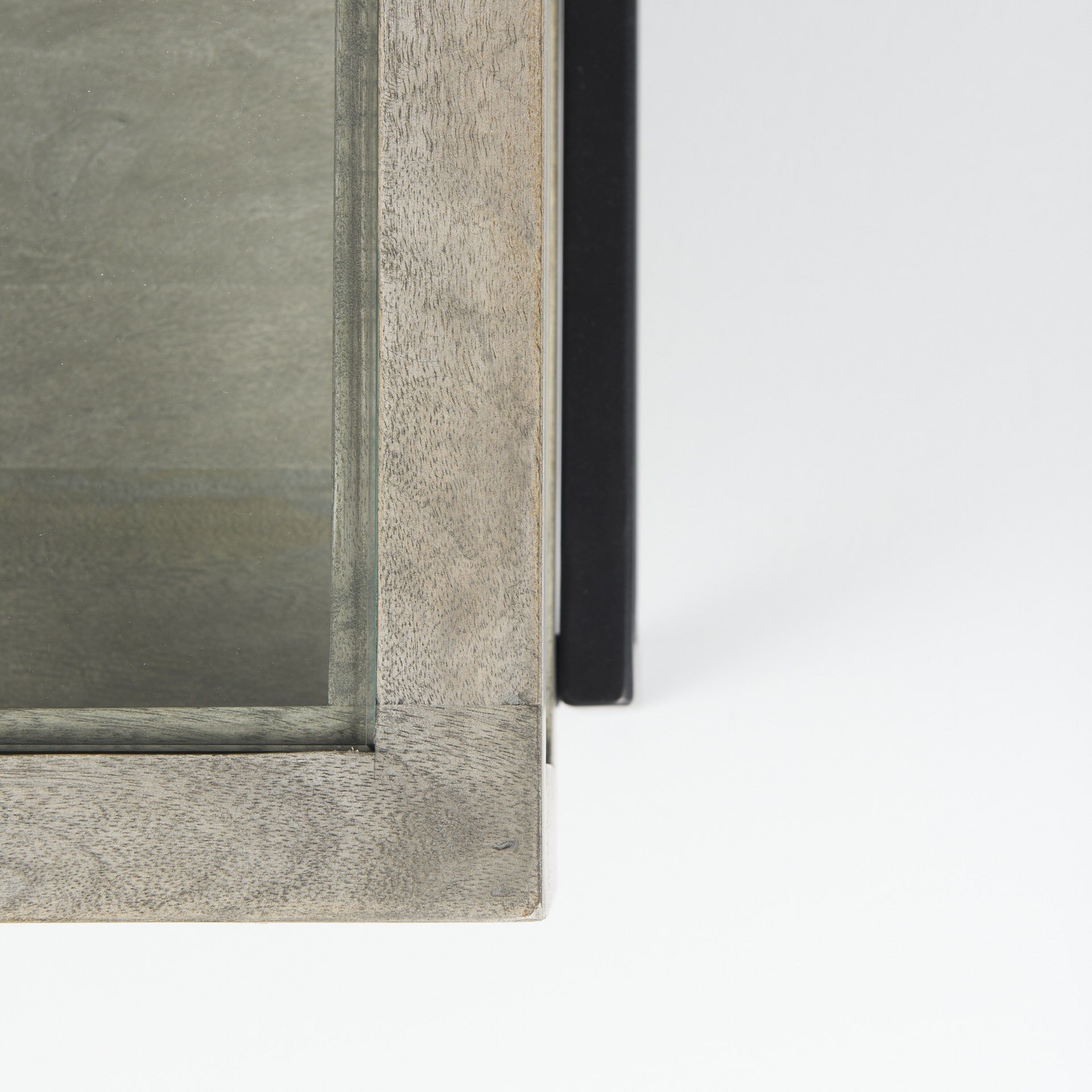 Square coffee table corner detail with gray wood-look paneling and black metal leg