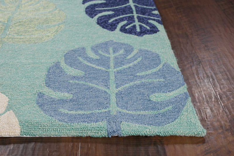 Corner of turquoise leaf-pattern rug with textured weave and multicolor leaves