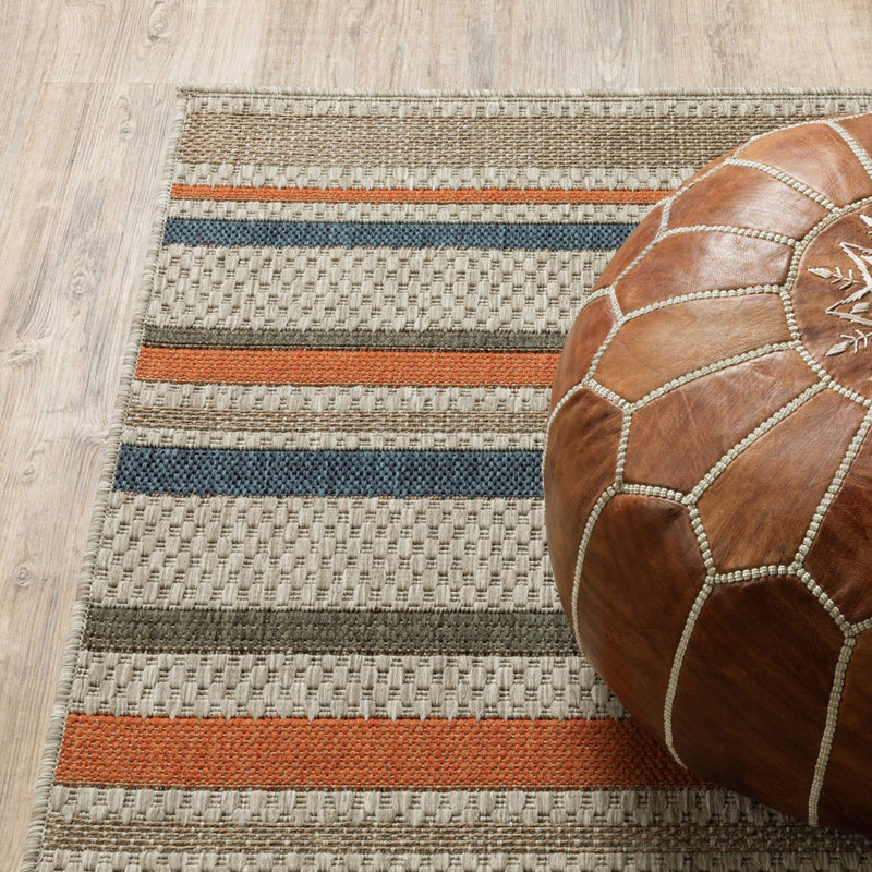 Striped area rug corner with textured weave; beige base with dark gray, orange, blue bars