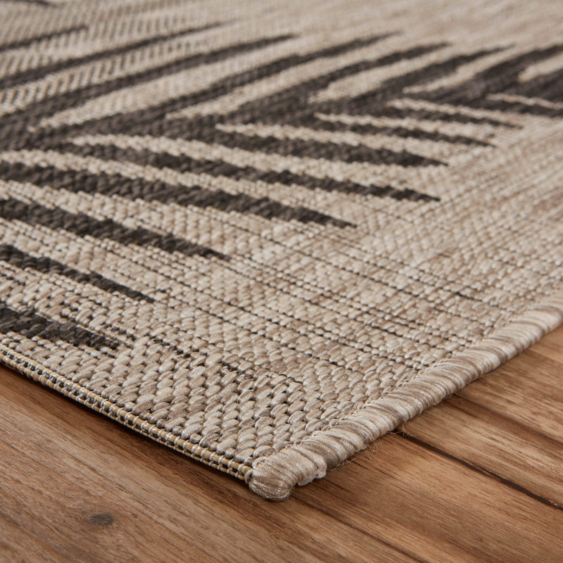 Beige and dark gray area rug corner with stitched border and flat woven texture