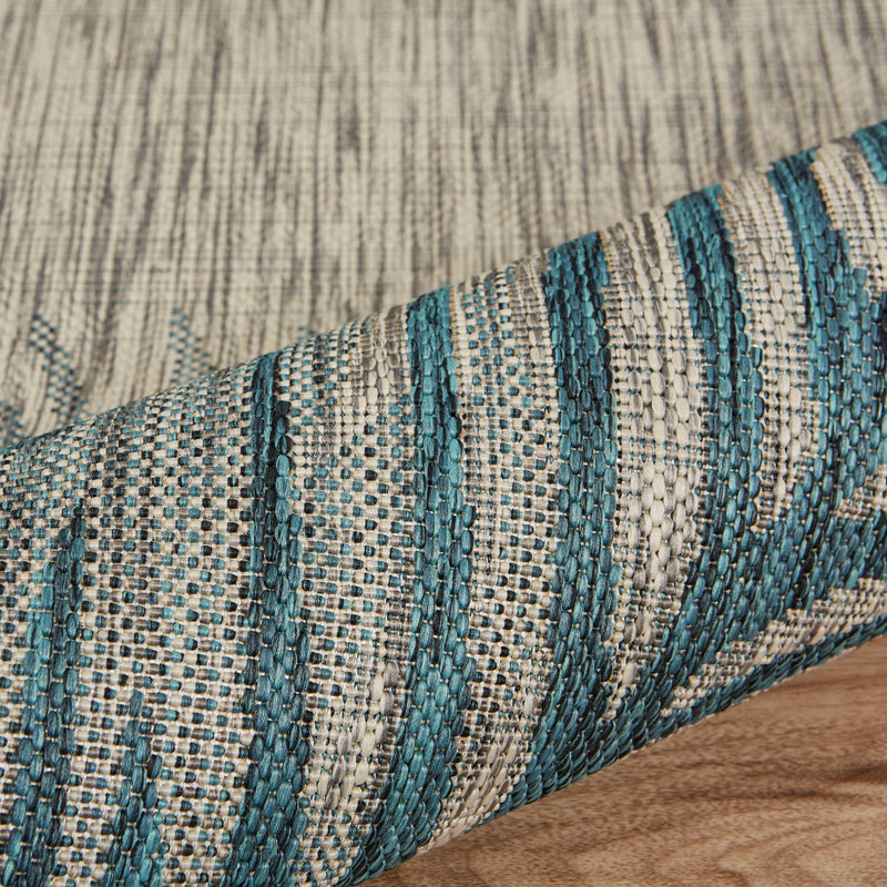 Close-up of woven area rug border with textured cream base and teal blue stripes.