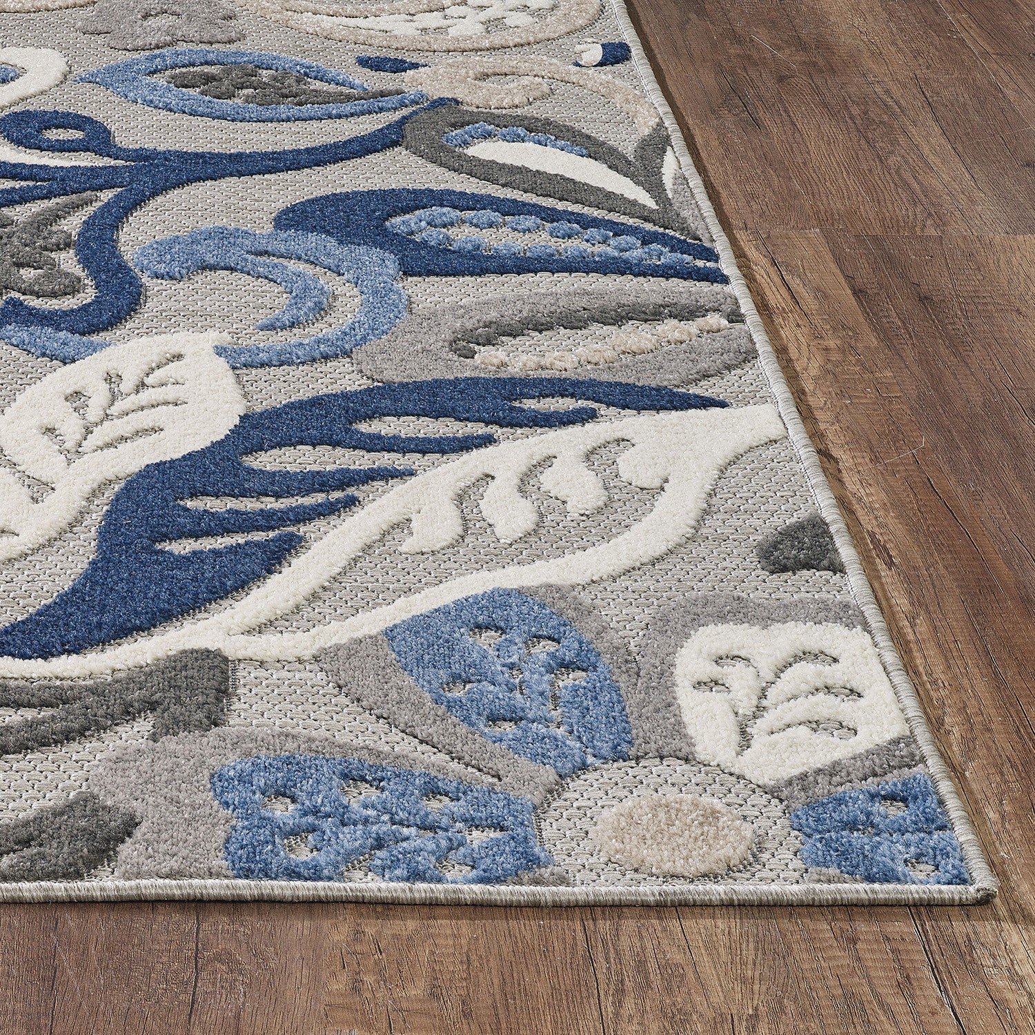 Blue, gray, and cream rectangular floral area rug with border on wood floor