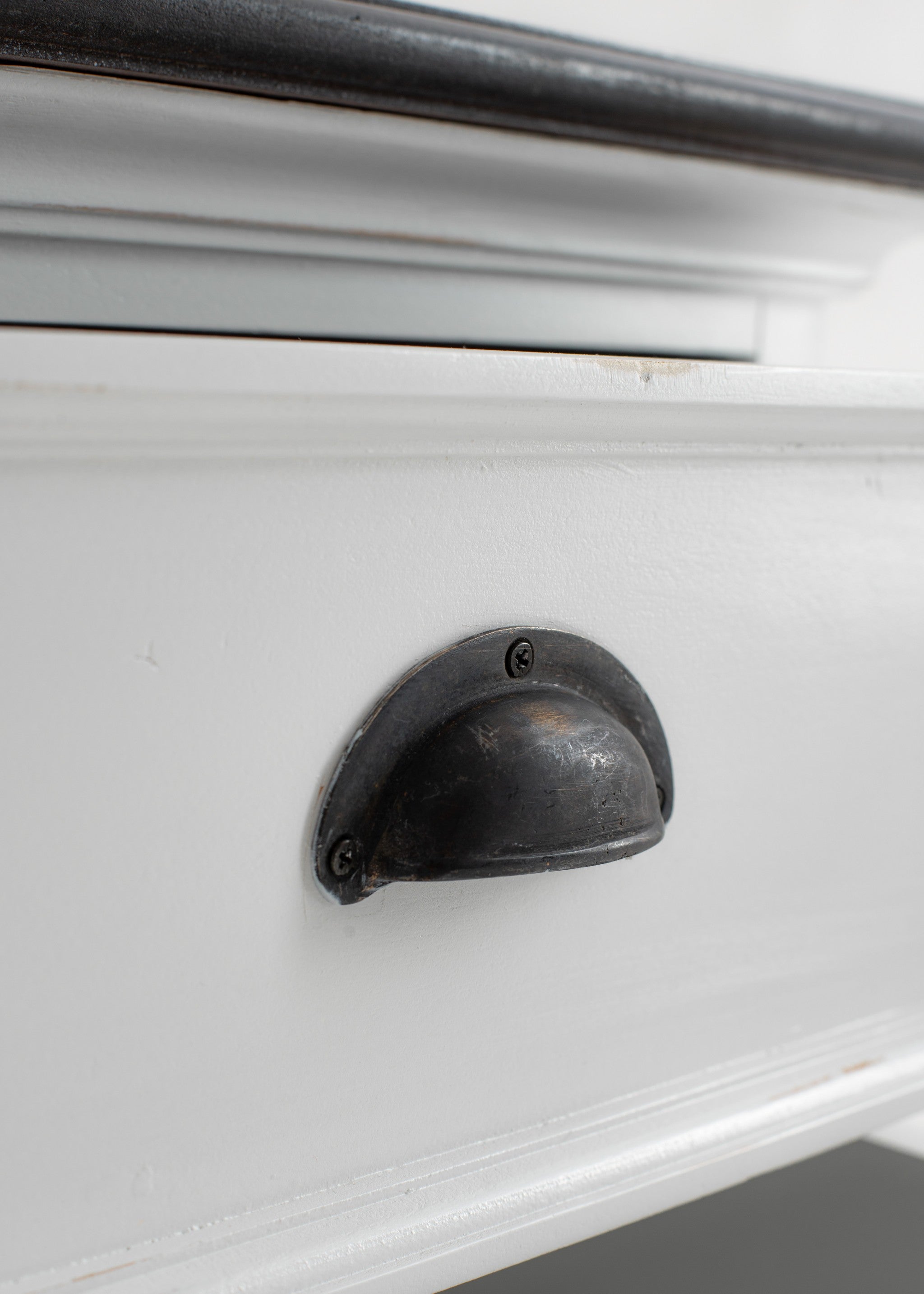 Black curved drawer pull on white nightstand drawer front
