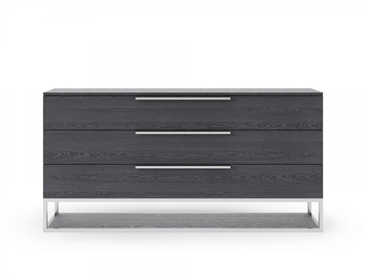 Grey three-drawer dresser with three metal bar pulls and open-frame base.