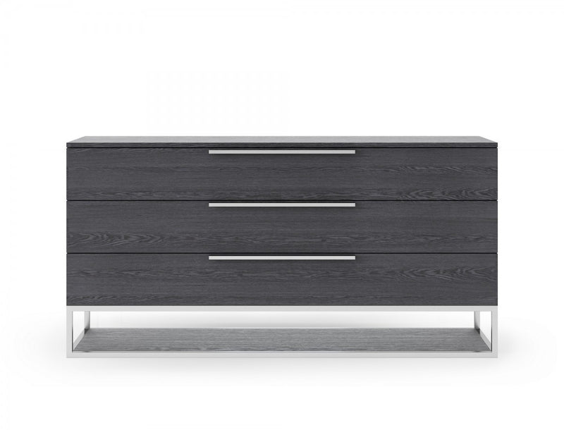 Grey three-drawer dresser with three metal bar pulls and open-frame base.