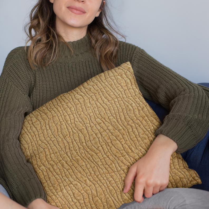 Yellow textured throw pillow with desert line pattern held by a person