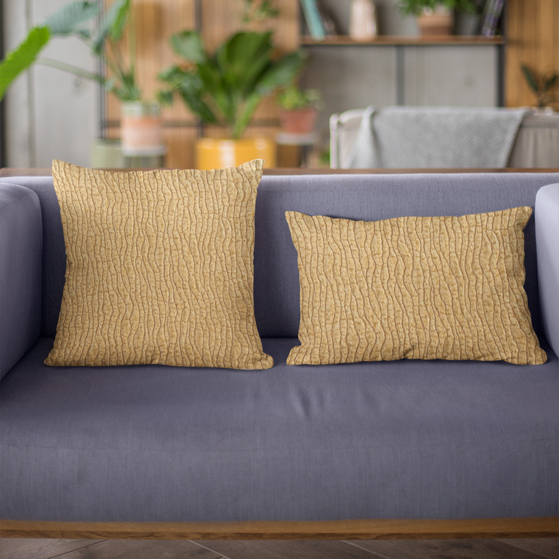 Two yellow throw pillows with wavy desert-line texture on a gray sofa