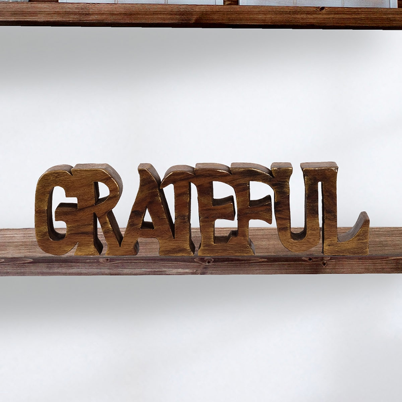 Wooden GRATEFUL letter sculpture on a shelf, close-up of carved letters