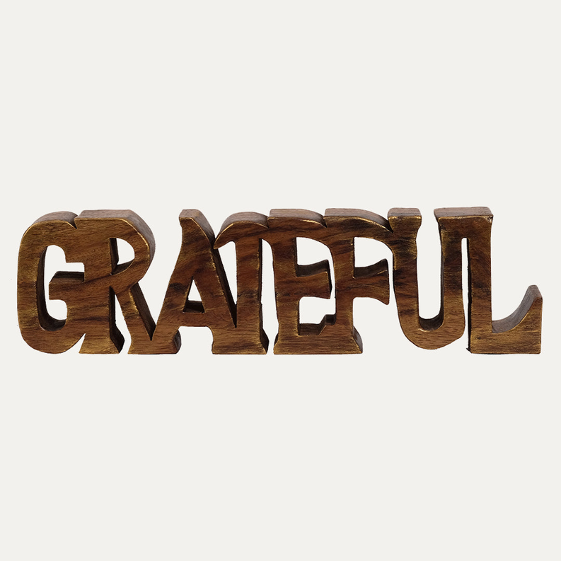 Wooden GRATEFUL letter sculpture, dark-brown carved letters on light background