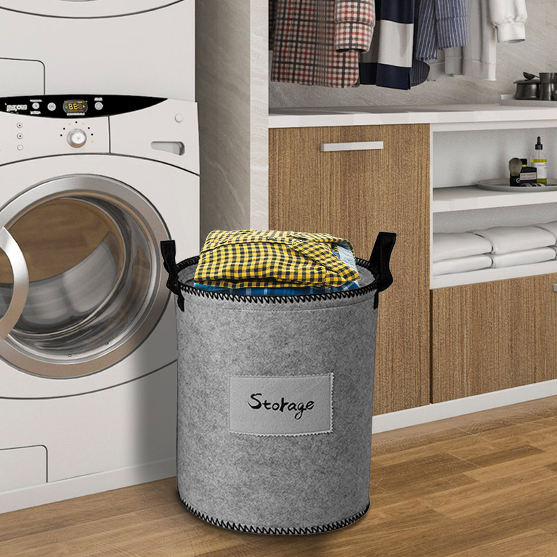 Gray felt laundry storage bin with “Storage” label and black handles, holding yellow folded cloth.