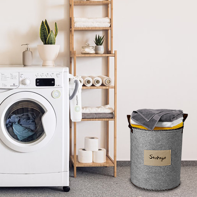 Gray felt storage bin with black handles and “Storage” fabric label, holding folded linens.