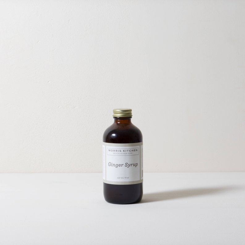 Amber-brown ginger syrup bottle with gold cap, front label visible on tabletop