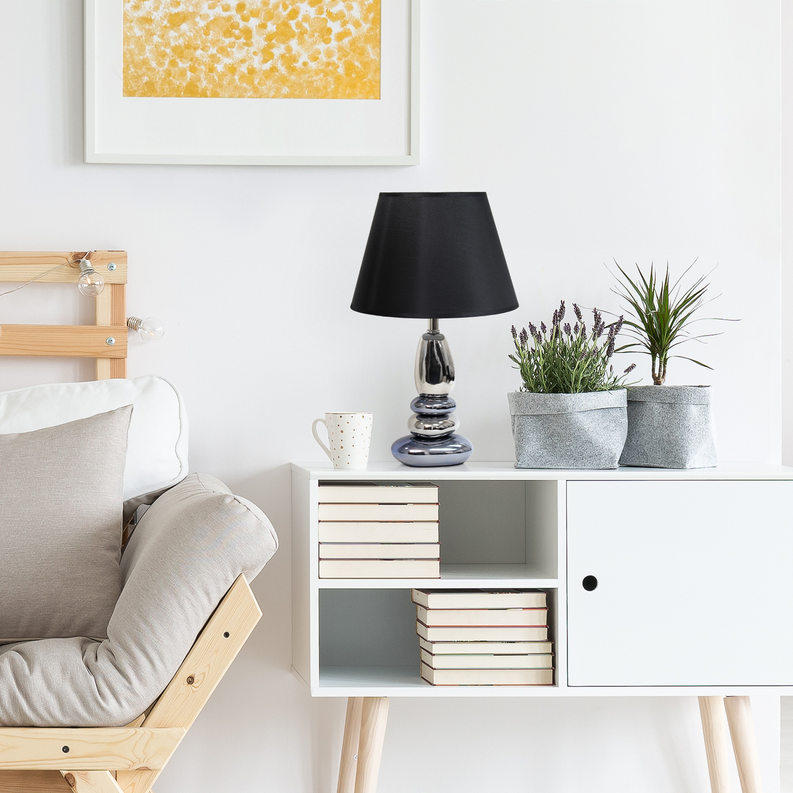 Black-shade chrome table lamp with stacked base on a cabinet