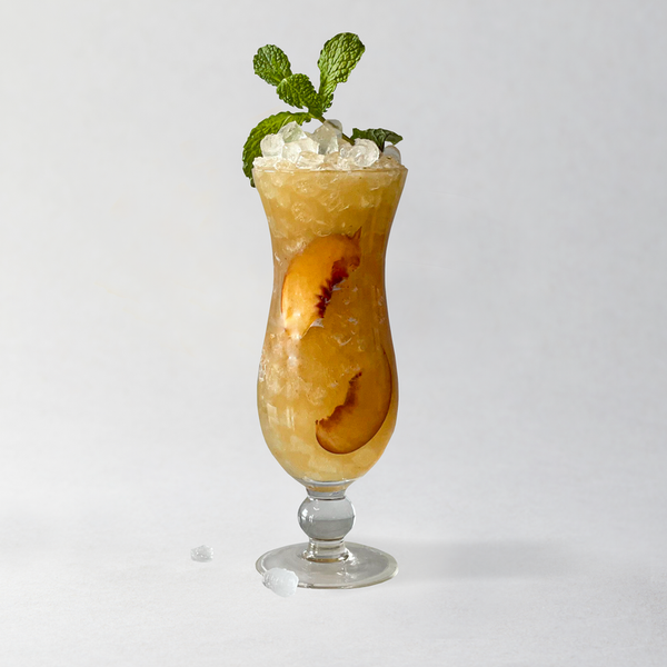Peach chamomile mixer in stemmed glass with ice, mint garnish