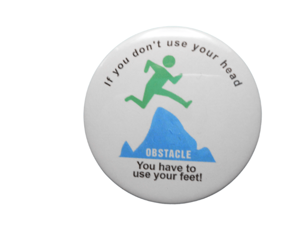 Round button with “don’t use your head” text and green/blue obstacle graphic