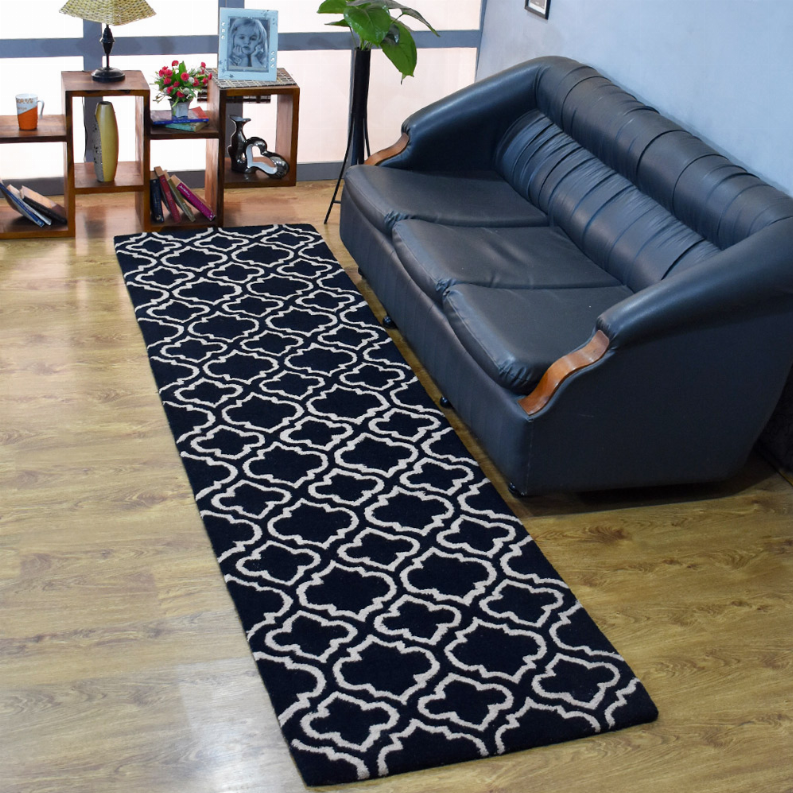 Black wool runner rug with ivory repeating quatrefoil trellis geometric pattern.