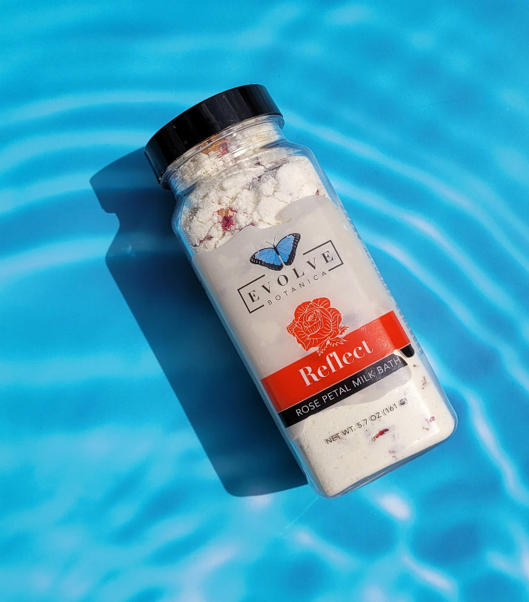 Milk bath soak bottle with rose petal theme, black cap, jarred pale dry powder inside.