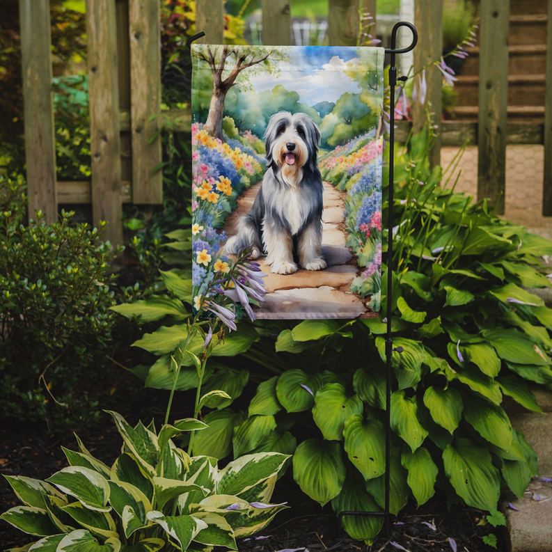 Bearded collie yard flag showing a dog on a path scene in a blooming garden